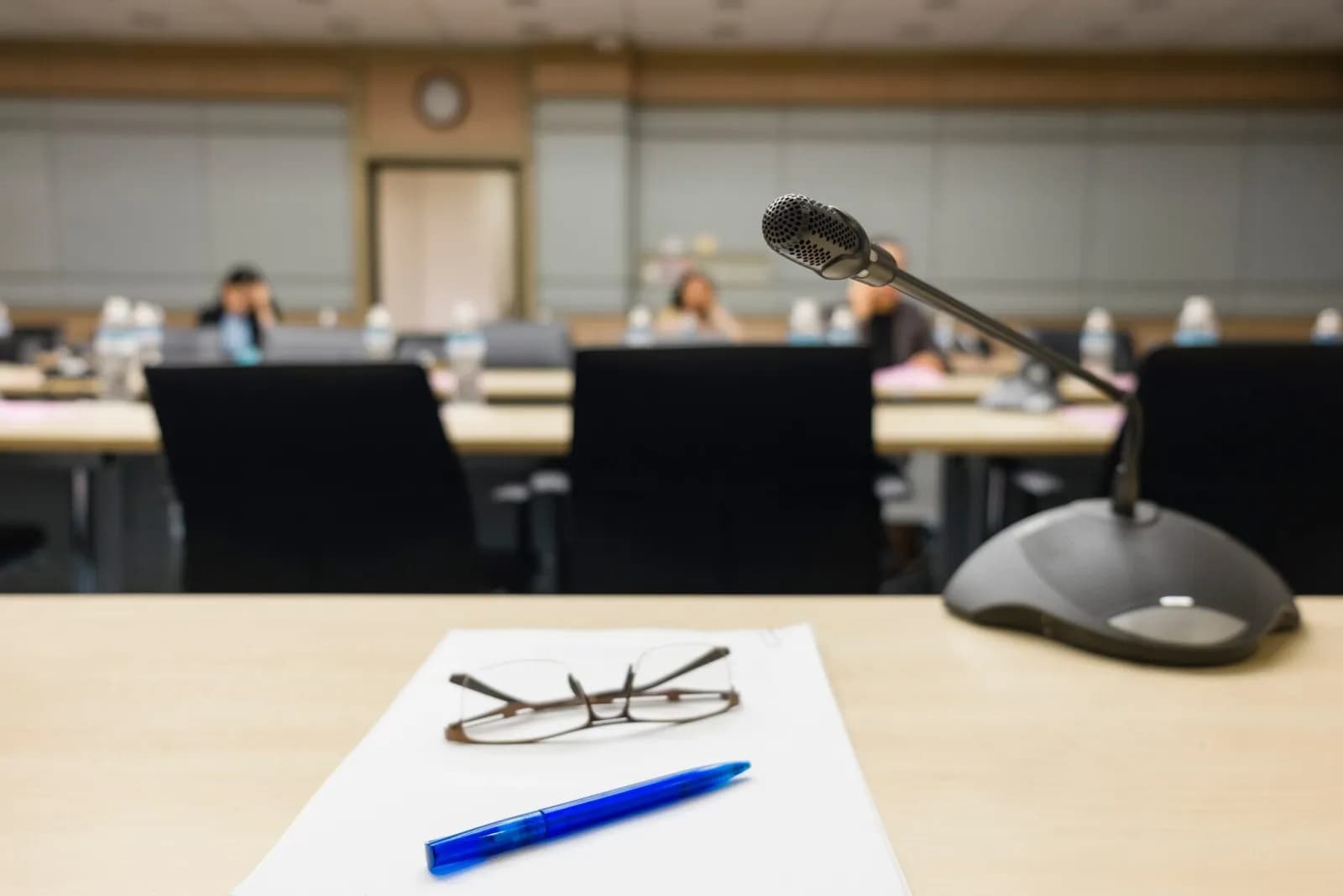 desk with glasses, pen and microphone governing board