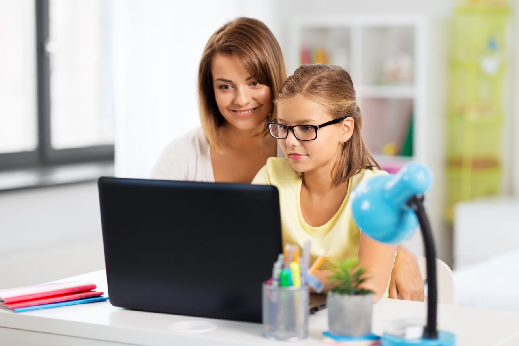mother and daughter with laptop doing homework