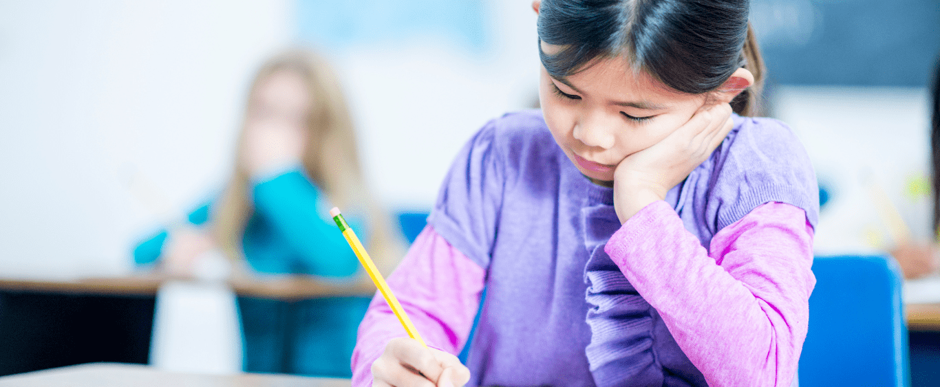 girl in a pink sweater writing with a pencil